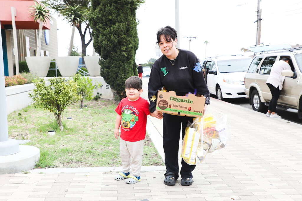 Mother and son standing with box of fresh produce