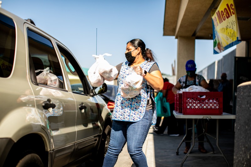 Volunteer at Feeding San Diego mobile food pantry placing bags of food into car.