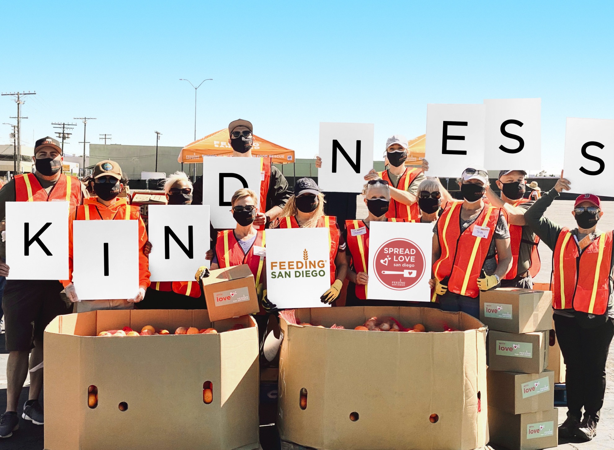 Volunteers at distribution hold up letters to spell "Kindness"