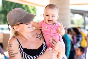 Woman holding smiling baby at Feeding San Diego food distribution in Oceanside