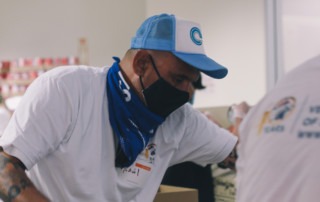 Veterans village volunteer packs boxes of food at Feeding San Diego distribution center