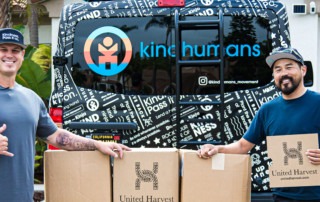 Lonie Pacton poses with Kind Human truck and donations for Feeding San Diego