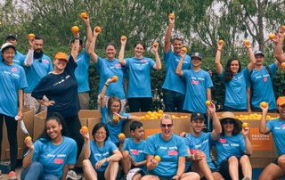 Group of volunteers poses with oranges after residential harvest