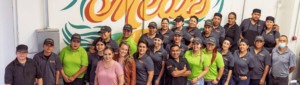 Top Notch Catering employees pose for photo in front of mural