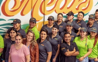 Top Notch Catering employees pose for photo in front of mural