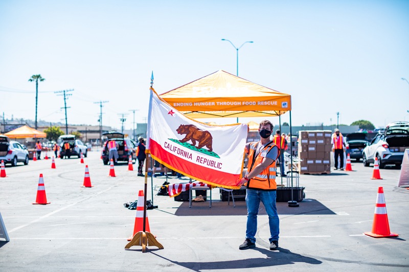 Volunteer leader holds California flag at Feeding San Diego distribution