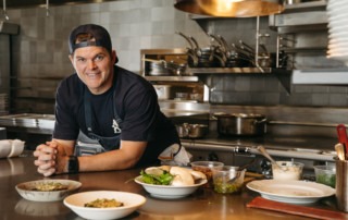 Chef Travis Swikard poses in front of prep dishes