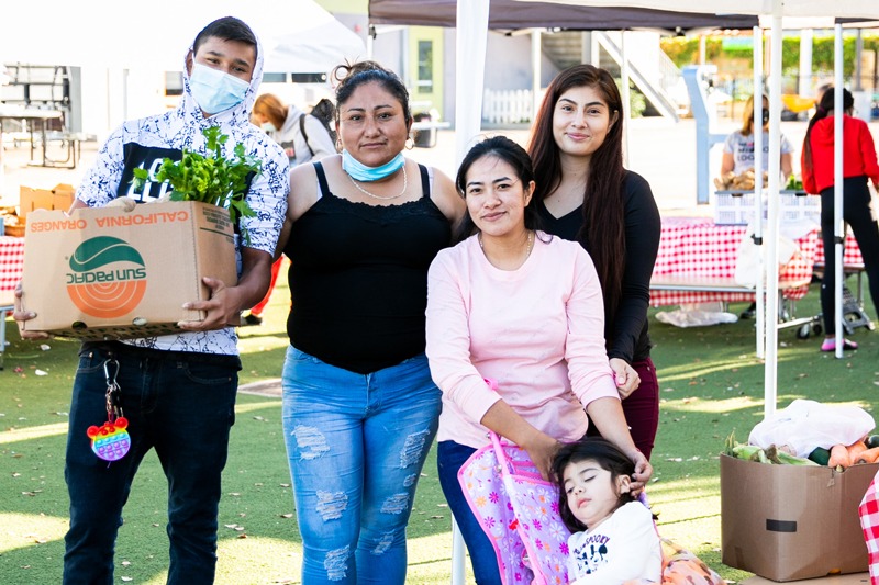 Family stands with food from free distribution in Barrio Logan