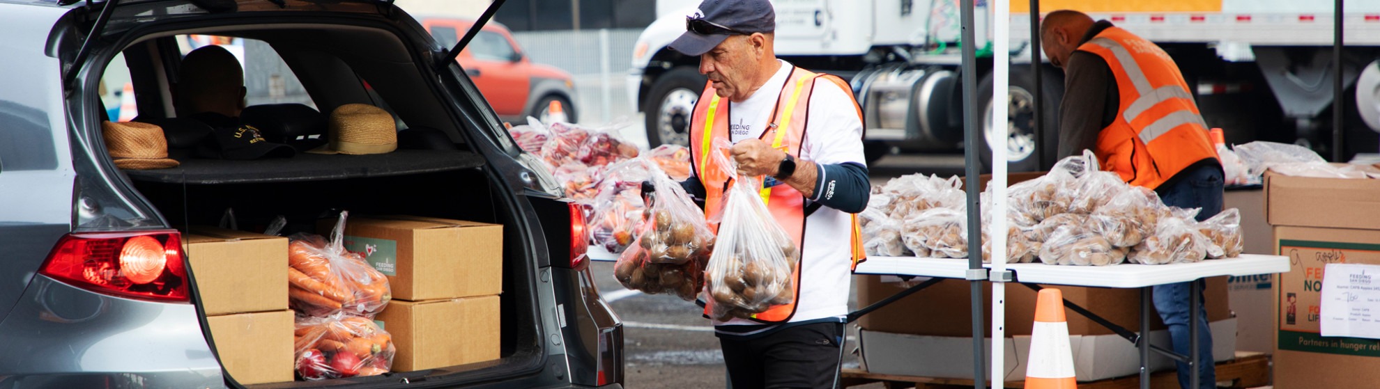 Volunteer places food into back of car at free food distribution