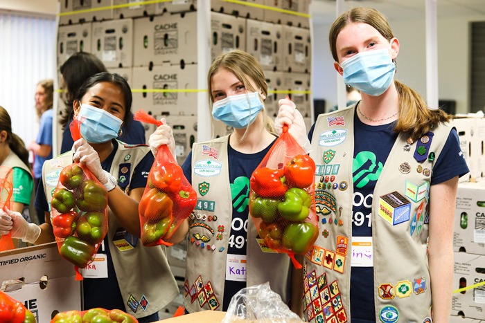 Girl scouts hold bags of apples at Feeding San Diego's volunteer center