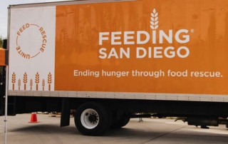 A Feeding San Diego truck parked next to an orange pop-up tent for a mobile pantry in Alpine