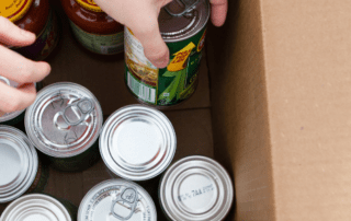 Hands packing cans into a cardboard box