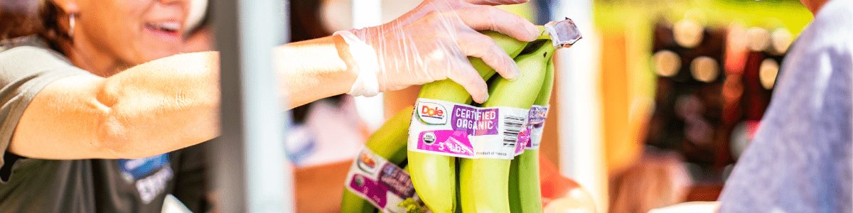 A woman handing out bananas at a Feeding San Diego food distribution