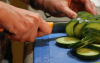 Close up of someone chopping a cucumber