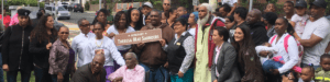A group of people in a park holding a sign that says "Honorary Theresa Mae Saunders"