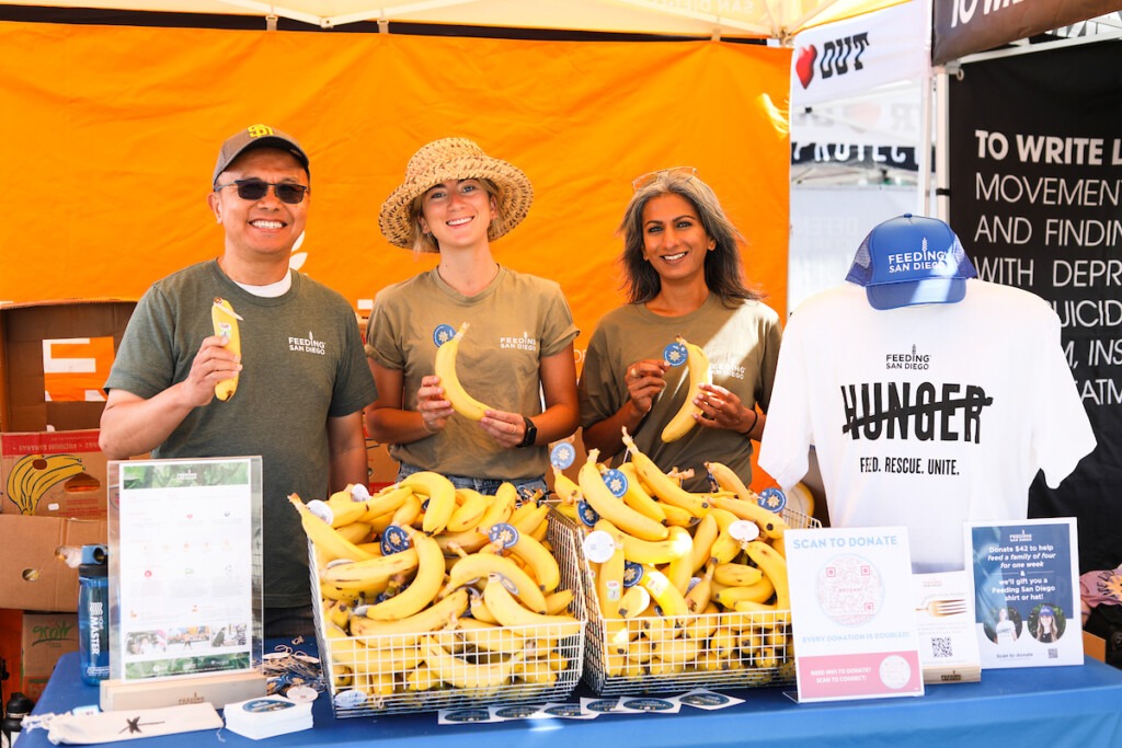 Bro-Am-Beachfest_6.18.22-01 Three people holding bananas at Feeding San Diegos' Bro-Am booth