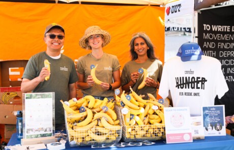 Three people holding bananas at Feeding San Diegos' Bro-Am booth