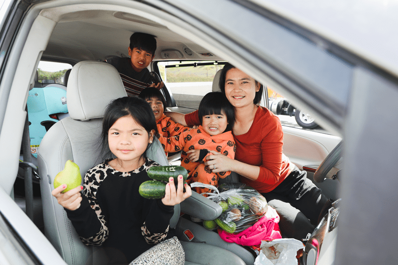 A mom with four kids in a car with fresh produce from a Feeding San Diego food distribution