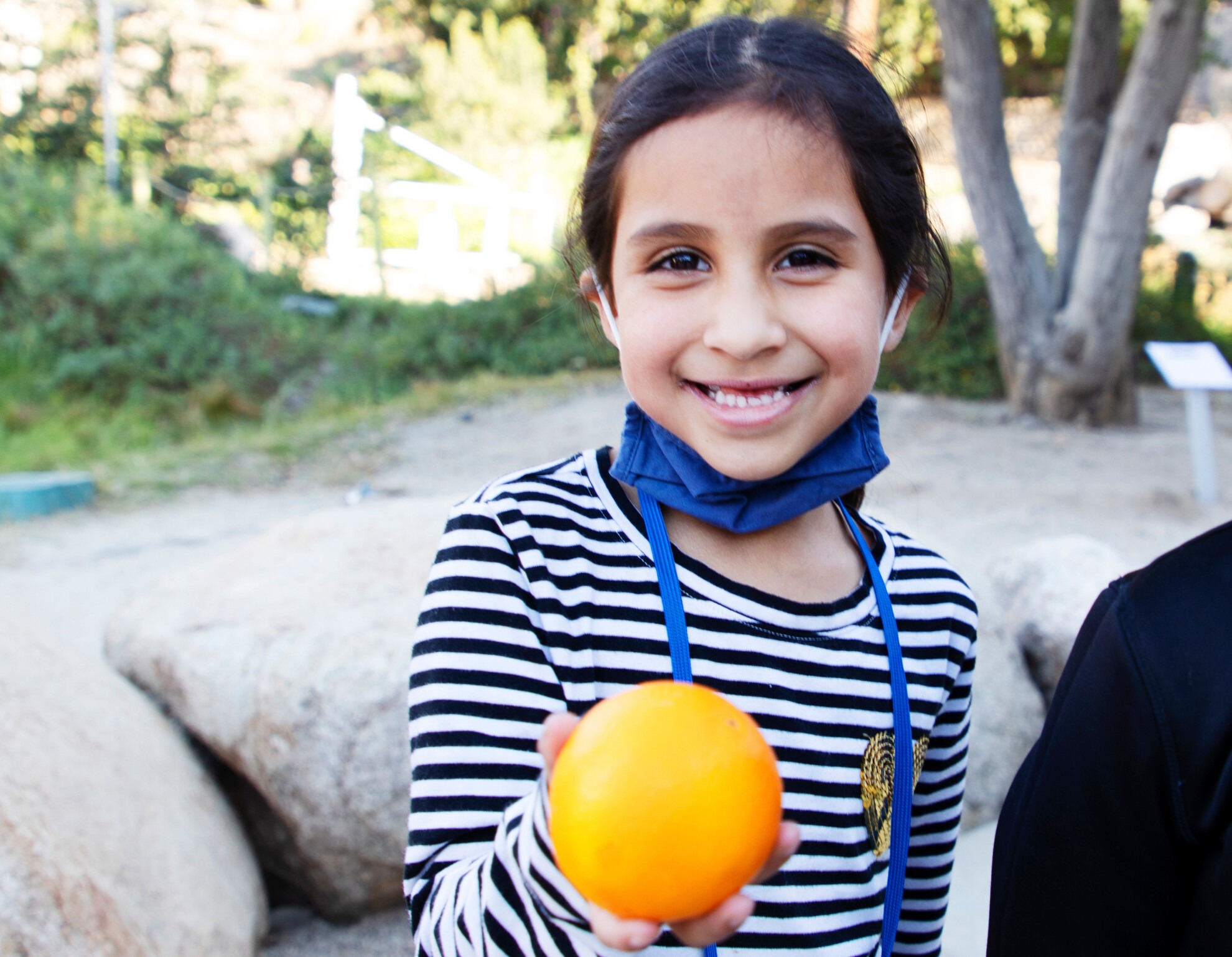 Girl holding an orange and smiling