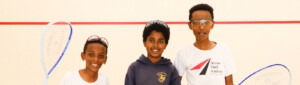 Three young students pose on racketball court