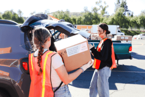 Volunteers load a box into a waiting car
