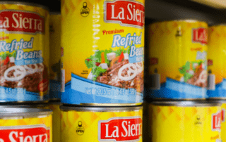 Cans of refried beans stacked on a shelf