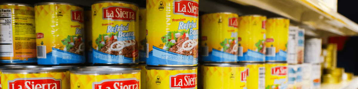 Cans of refried beans stacked on a shelf