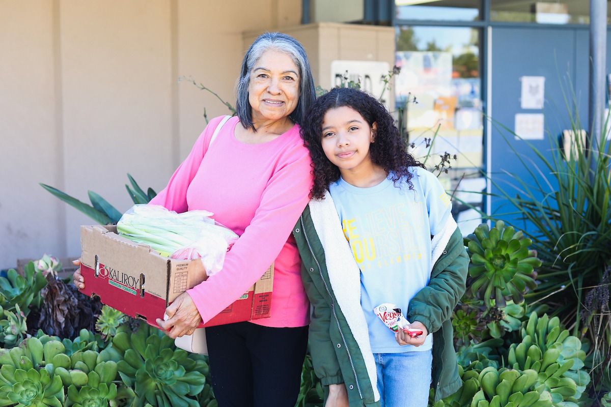 Woman and her daughter standing with box of produce