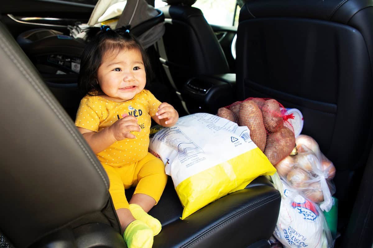 Baby smiling in back seat of car with fresh produce