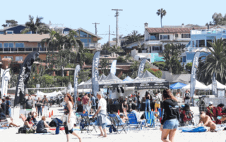 A crowd and stands at the Switchfoot Bro-Am Beach Fest