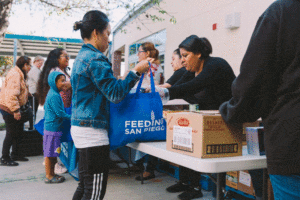 A woman receives food from a volunteer at a school pantry