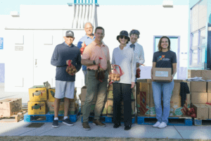 A group of volunteers holding produce and food boxes at a Feeding San Diego school pantry