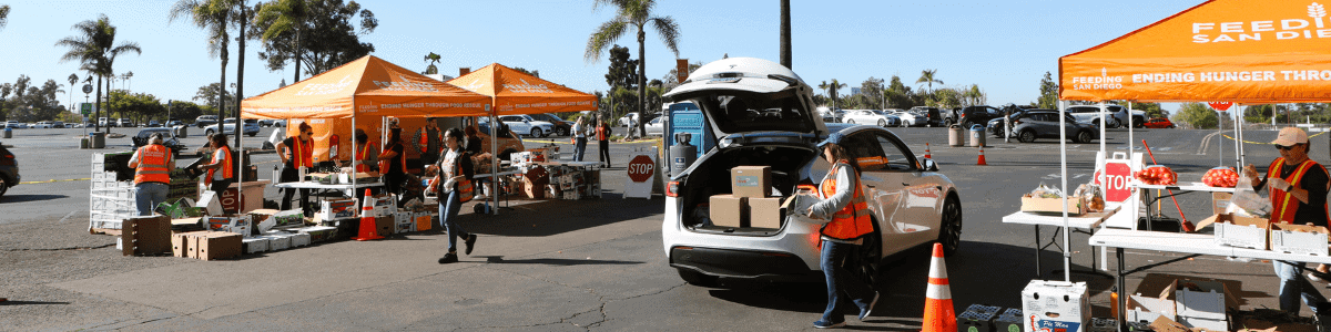 Volunteers load food into the trunk of a car at a holiday food distribution