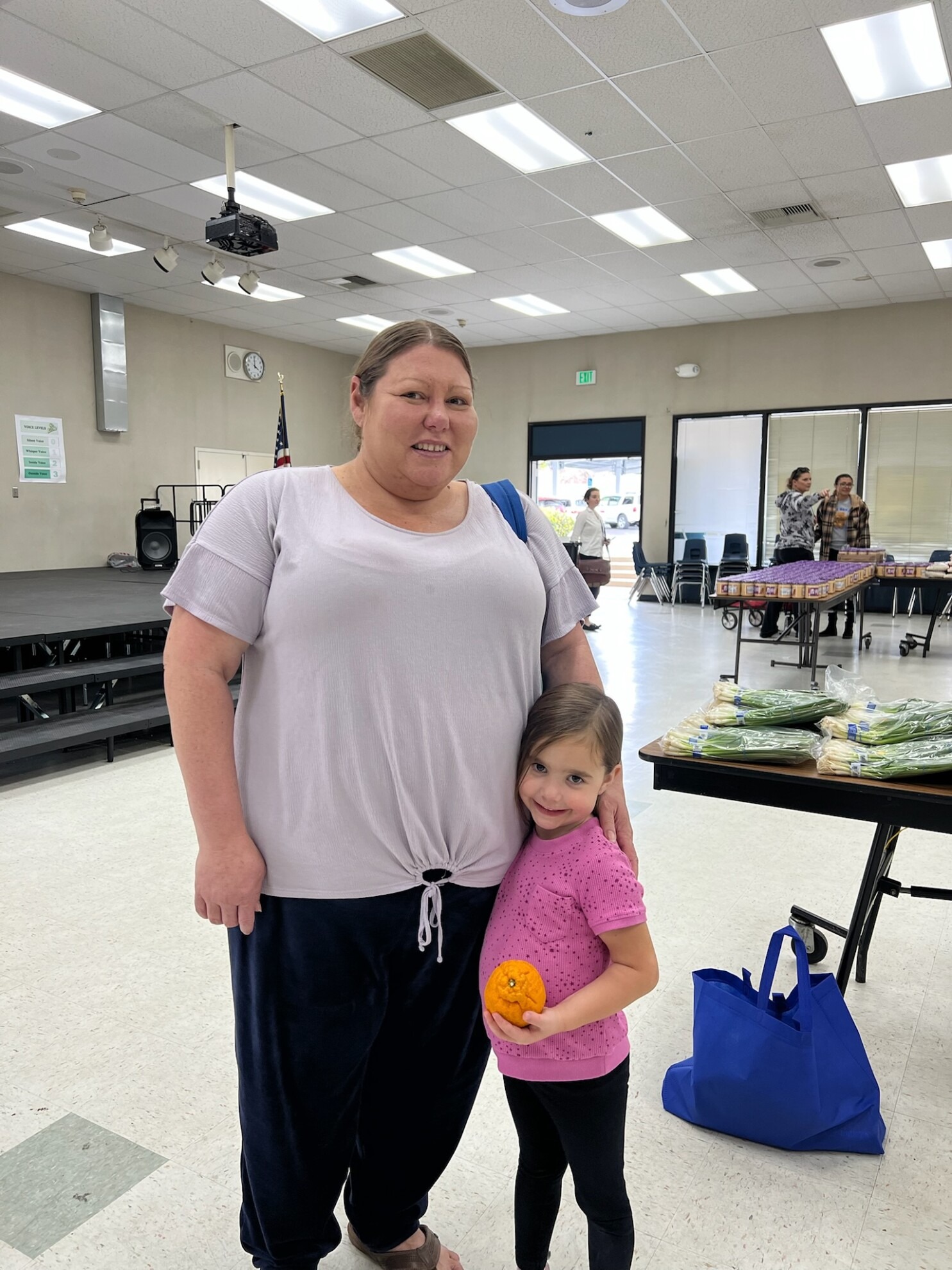 A woman and a young girl holding an orange at a Feeding San Diego school pantry