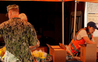 A man in uniform picks up food from a Feeding San Diego distribution