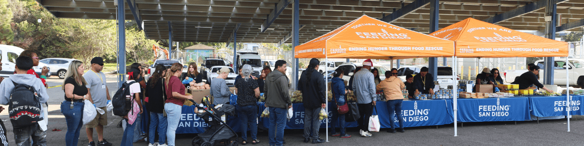 A line of people standing in front of orange pop-up tents