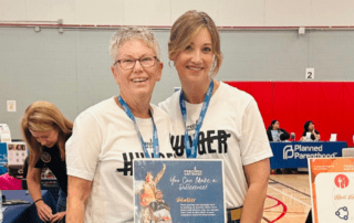 Two smiling women standing behind a table at an event