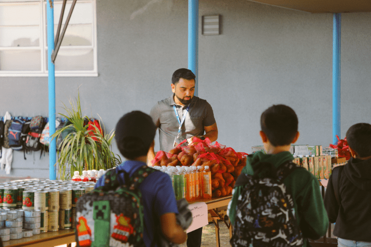 Kids with backpacks picking up food at a school pantry