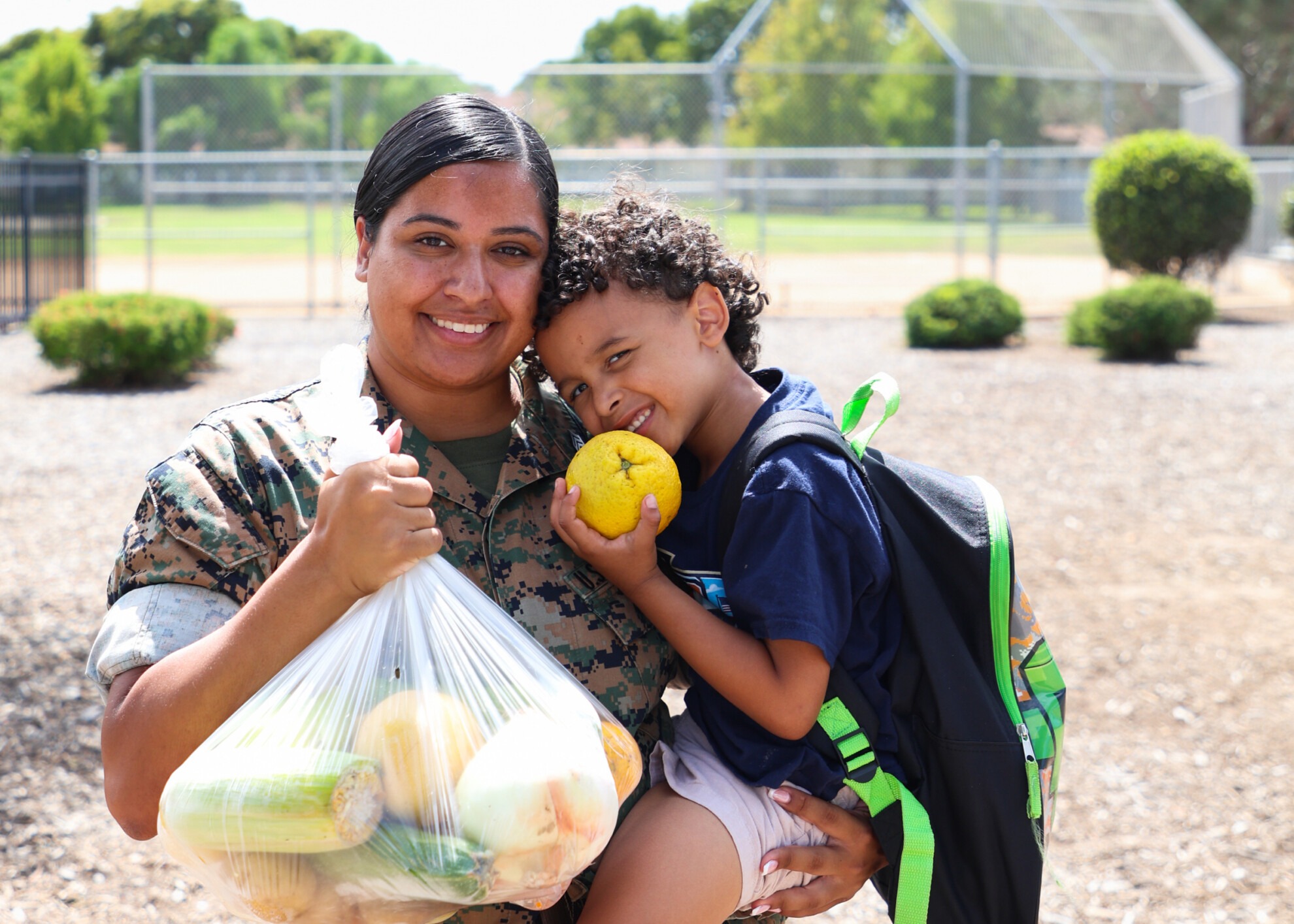 Woman holding a bag of produce and a smiling boy